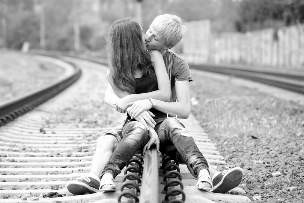 Couple kissing at railway. Photo in black and white style.